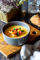 Cheese cream soup with grilled shrimp on a wooden background.