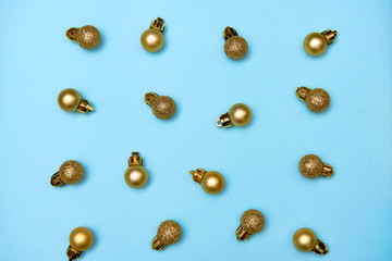 Creative Christmas pattern with golden shiny baubles on blue pastel background, copy space. Minimal, winter, new year concept. Top view, flat lay