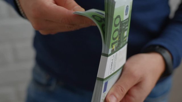 A man counts the money in a pack of Euro banknotes with a face value of one hundred euros large, hands