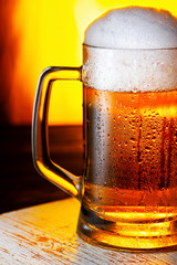 Light Beer Mug with White Foam on Wooden Table and Yellow Background Close Up