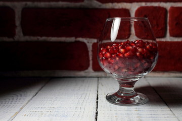 Red pomegranate grains in a glass, pomegranate juice.