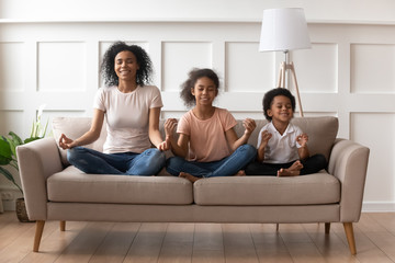 African mother with son and daughter practises yoga indoors