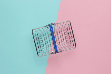 Mini shopping basket on pink blue pastel background. Top view
