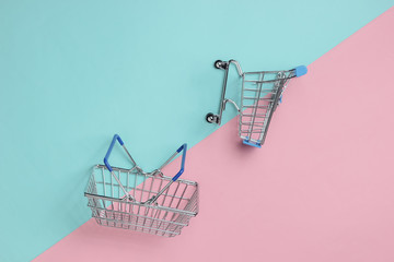 Minimalistic shopping concept. Shopping trolley, basket on blue pink pastel background. Top view