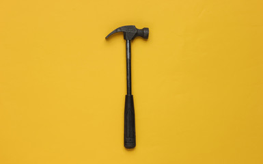 Hammer on yellow background. Top view, minimalism