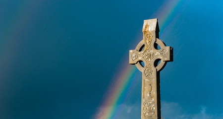Rainbow over ancient Irish cemetery Celtic cross