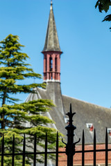 Focus on foreground fence in shadows. Street view of beautiful historic city center architecture of Bruges or Brugge, West Flanders province, Belgium. Lovely summer August weather