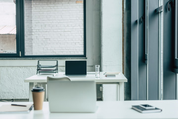 office desks with laptops, coffee to go and glass of water, notebooks and documents tray