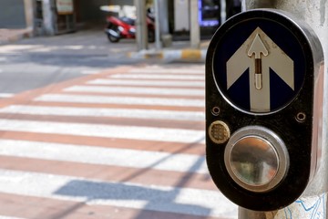 Pedestrian crossing button next to zebra crossing for press and wait signal across to opposite the road.