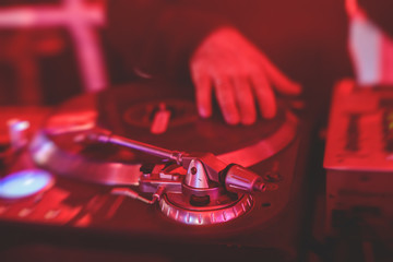 View of Dj mixer and vinyl plate with headphones on a table with DJ playing and mixes the track in...