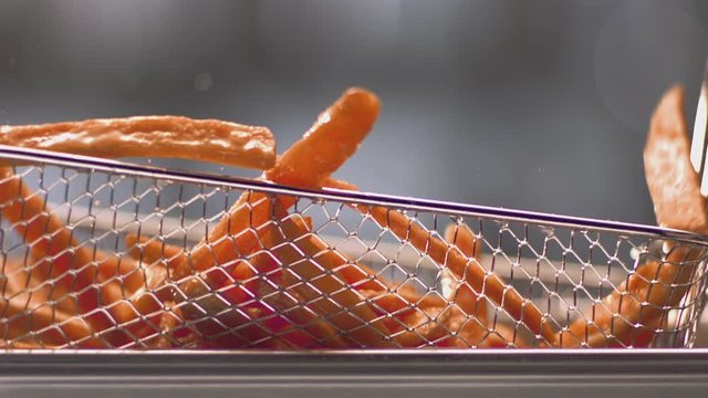 French fries tossed in deep fryer basket in slow motion 