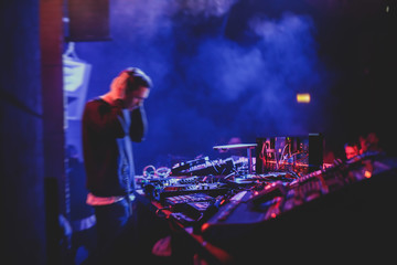View of Dj mixer and vinyl plate with headphones on a table with DJ playing and mixes the track in...