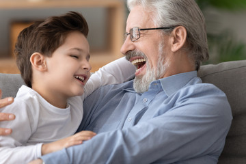 Happy laughing grandfather playing, hugging adorable little grandson