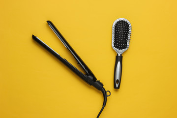 Hair care. Beauty studio shot. Hair iron, comb on  yellow background. Top view