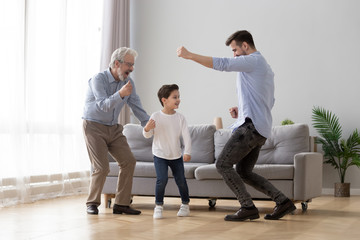 Happy grandfather, father and little son having fun, dancing together