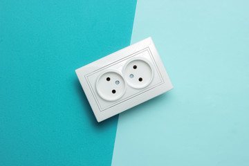 Double power socket on a blue pastel background. Top view. Studio shot