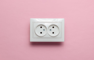 Double power socket on pink wall. Studio shot. Minimalism
