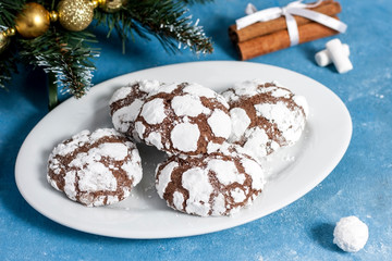 Delicious marble cookies strewn with icing sugar. New Year's gingerbread cookie on a blue background with cinnamon, snowflakes and marshmallows. Homemade festive baking for the New Year and Christmas.