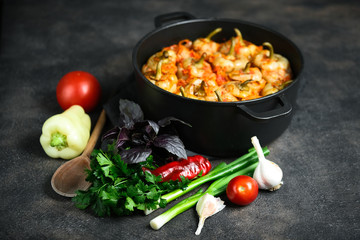 Stuffed peppers with rice, meat and spices in a dark pan on a dark background.