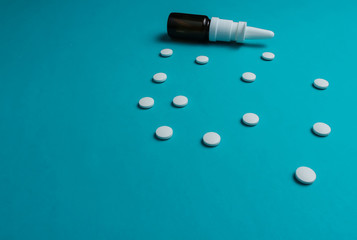 White pills, nasal spray on blue background. Minimalistic medicine still life