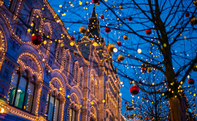 Christmas lights on the tree trunk, closeup. Blurred background city street with Christmas illuminations. Christmas and New Year holiday background. Vintage color tone. Copy space for your text.