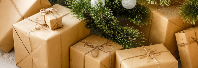 New Year's gifts under the Christmas tree. The gifts are packed in kraft paper and tied
