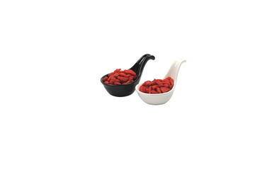 Dried Chinese Wolfberries or Goji berries in black and white ceramic spoons isolated on white background.