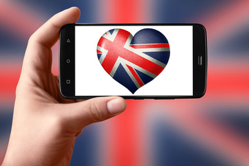 British flag in the shape of a heart on the phone screen. Smartphone in hand shows a flag heart.