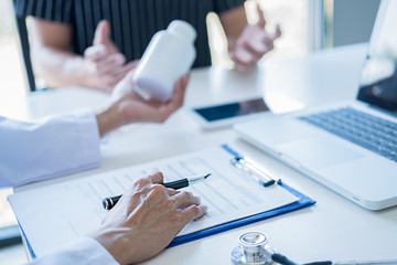 Patient listening intently to a male doctor explaining patient symptoms or asking a question as they discuss paperwork together in a consultation