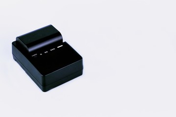 Charger with rechargeable battery of camera on white background.
