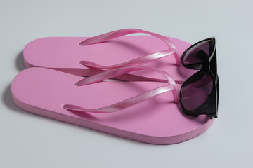 Summer beach concept. Sunglasses, flip flops on white background. Top view