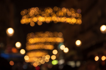 Blurry photo of street at night in city downtown decorated with beautiful Christmas lights garland. Winter holidays vacation and travel in Europe  concept. Festive urban blurry background.