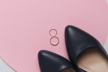 Bride shoes, golden wedding rings on pink pastel background. Top view