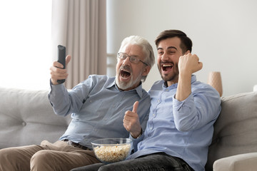 Excited old father and son watching tv, football match together