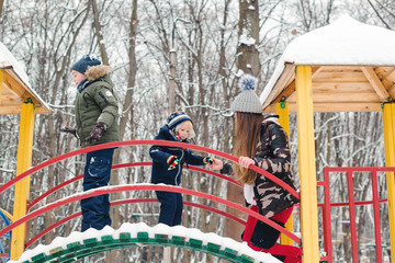 Mother with children at playground in winter park. Happy and healthy childhood