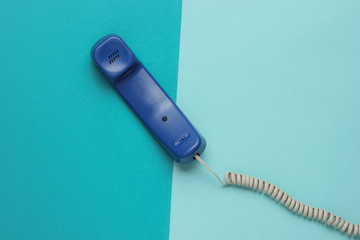 Handset on blue paper background. Minimalistic office concept. Top view