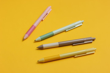A lot of colored pens close-up on yellow background.