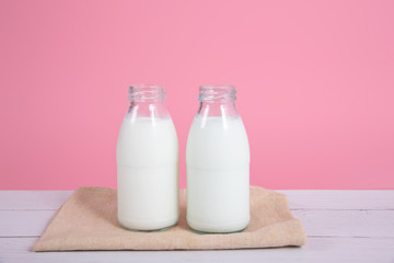 Milk bottle on table with pink background.