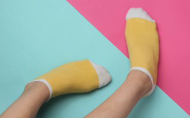Female legs with yellow socks on pink blue studio background. Pastel color trend. Minimalistic fashion concept. Top view