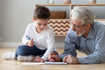 Grandfather playing with little grandson, drawing colored pencils