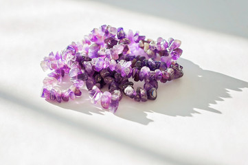 Ancient colorful healing crystals or gemstones on a white background: Amethyst necklace bring positive energy, inner peace and open third-eye chakras