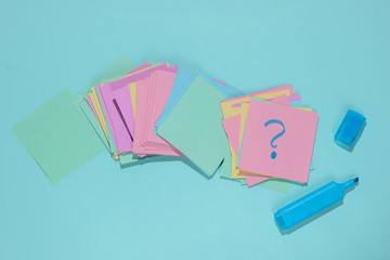 Minimalistic office concept. Lot of memo papers with question mark and felt-tip pen on blue background. Top view