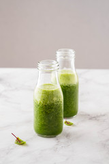 Blended green smoothie with ingredients on the white table.