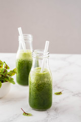 Blended green smoothie with ingredients on the white table.