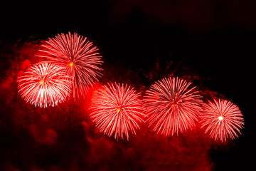 Flashes of red fireworks against black sky
