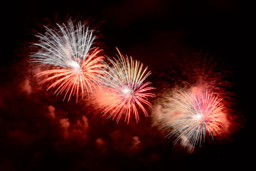 Flashes of red, green and white fireworks against black sky