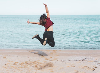 A Woman travel blogger enjoying happiness at wander trip. Wanderlust vacation concept with young influencer girl around the world. girl jumps on the sand - desaturated pastel colors