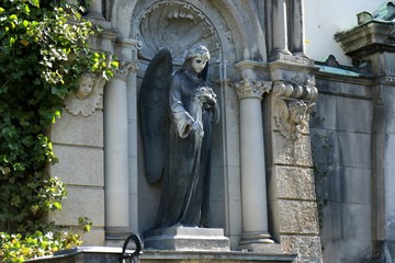 Sculpture of an Angel with flowers (roses) in her hand on a family tomb / crypt at the cemetery at Suedstern