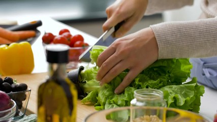 healthy eating, vegetarian food and cooking concept - woman adding lettuce to salad bowl at home kitchen - Powered by Adobe