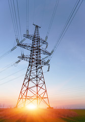 High-voltage power lines at sunset or sunrise. High voltage electric transmission tower